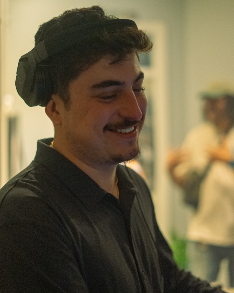 DJ OTEO authentic teeth-showing laugh, headphones on top of head signature pose